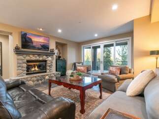 Experience luxurious living in this stunning great room, featuring a magnificent stone fireplace and a large flat-screen TV perfect for cozy evenings.
