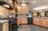 This modern kitchen features sleek stainless steel appliances, including a gas range and dishwasher, complemented by elegant granite countertops and a striking marble backsplash.
