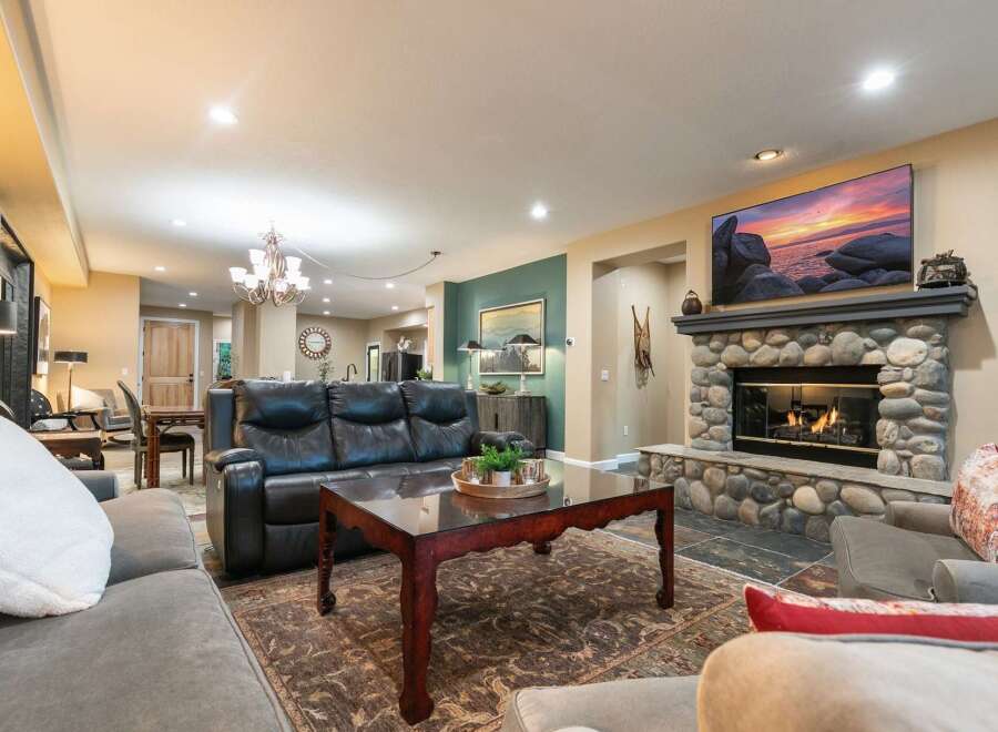 Experience ultimate comfort in this spacious living room, featuring a large stone fireplace and a mounted flat-screen TV, perfect for cozy evenings.