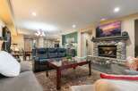 Experience ultimate comfort in this spacious living room, featuring a large stone fireplace and a mounted flat-screen TV, perfect for cozy evenings.