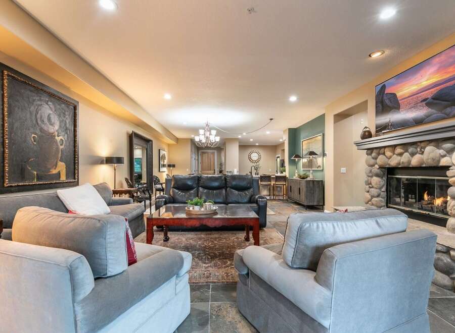 Experience luxury living in this spacious great room, featuring a cozy stone fireplace and a large flat-screen TV perfect for entertaining.