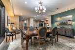 This spacious dining room features a large wooden table with upholstered chairs, perfect for family gatherings.