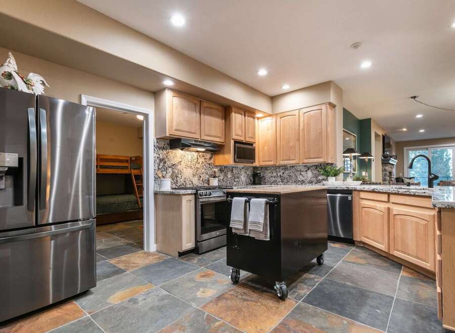 This spacious kitchen features a large stainless steel refrigerator and ample wooden cabinetry, perfect for storage.