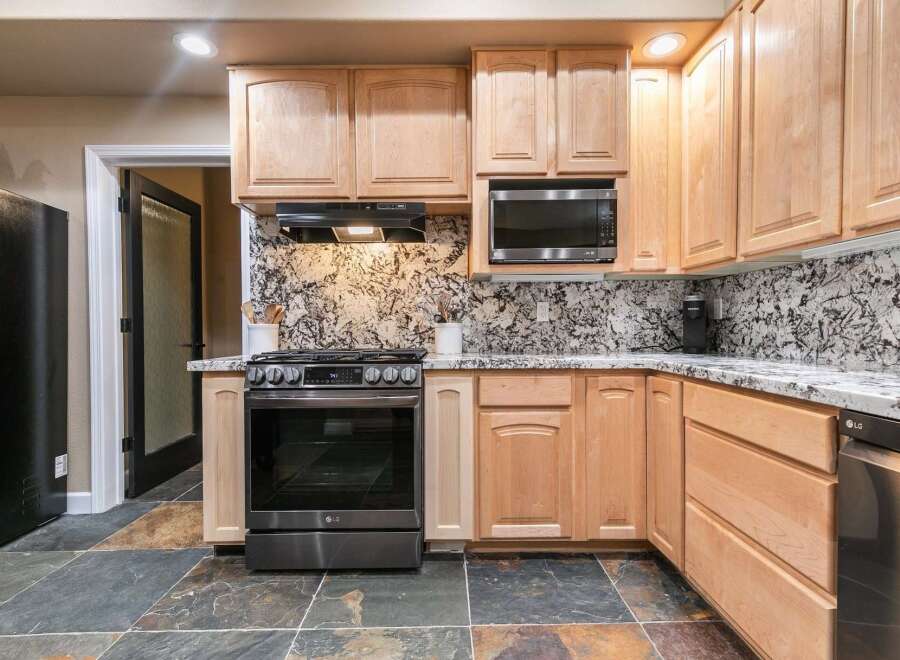 This kitchen features light wood cabinetry and a striking granite backsplash that adds a touch of elegance.