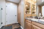 This bathroom features a white arched door leading to a tiled shower area and a tall wooden cabinet.