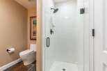 Experience modern comfort in this bathroom featuring a sleek, white tiled walk-in shower with black fixtures.