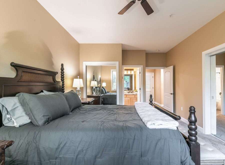 Experience luxury and comfort in this master suite, featuring a grand four-poster bed adorned with plush grey linens and accent pillows.