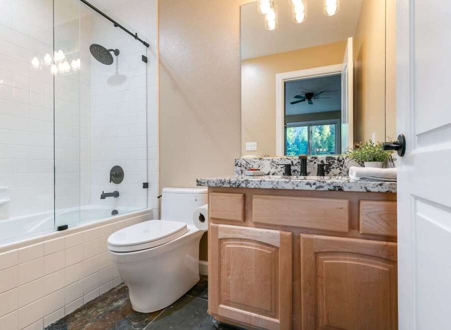 This modern bathroom features a sleek glass-enclosed shower and tub combination, complemented by a clean white tiled backsplash.