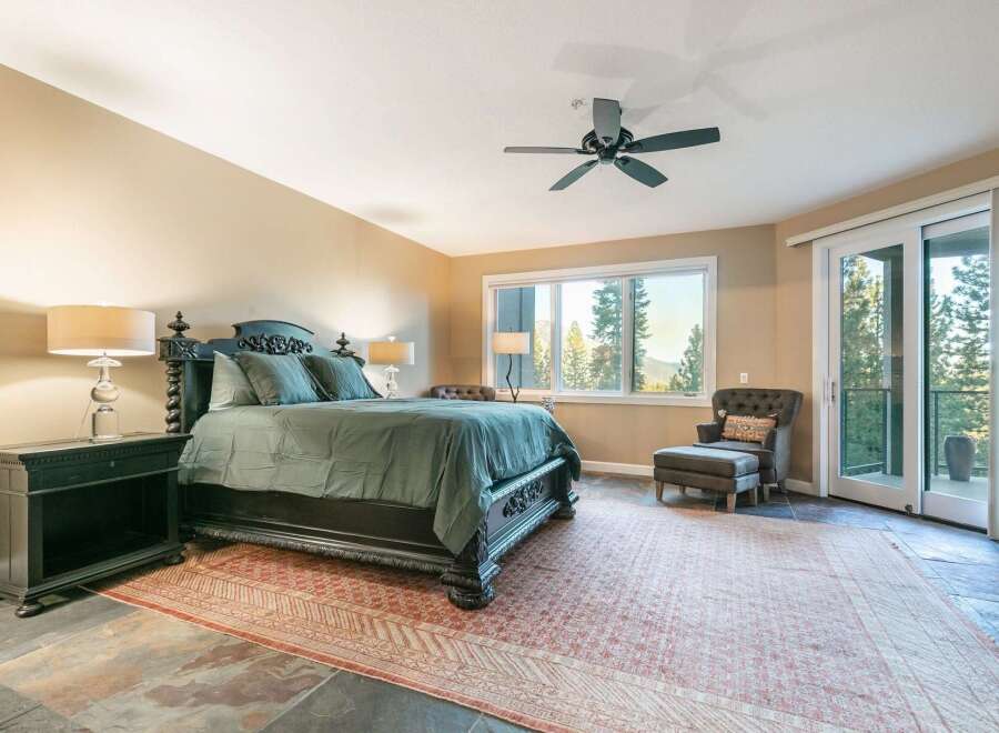 Experience luxurious mountain living in this stunning bedroom featuring a grand four-poster bed adorned with plush green bedding.