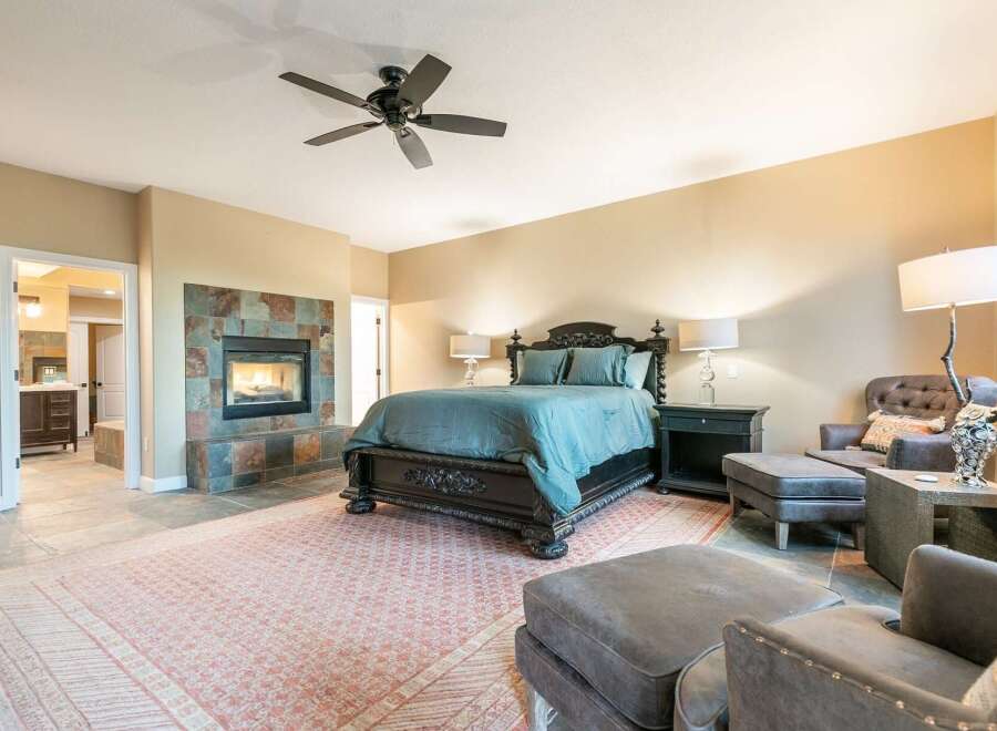 Experience luxury and comfort in this master suite, featuring a grand dark wood bed adorned with teal bedding.
