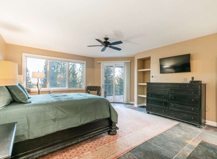 Experience luxurious mountain living in this stunning master bedroom, featuring a king-size bed with plush bedding and a private balcony overlooking a serene forest.
