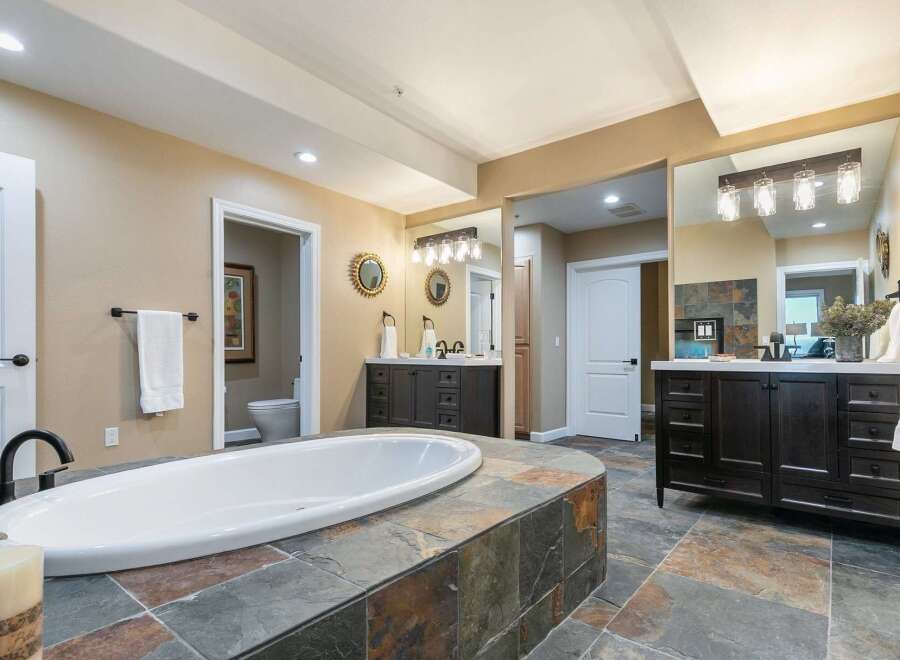 Indulge in luxury with this stunning master bathroom, featuring a spacious soaking tub set on a custom stone platform.