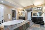 Indulge in luxury with this stunning master bathroom, featuring a spacious soaking tub set on a custom stone platform.