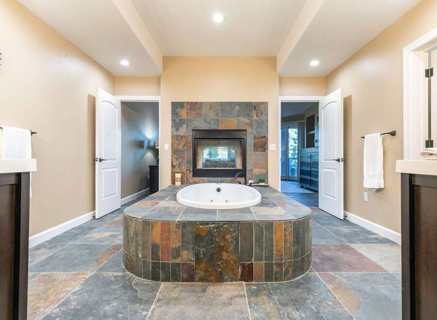 Indulge in luxury with this stunning bathroom featuring a spacious jacuzzi tub and a cozy fireplace.