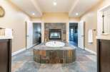 Indulge in luxury with this stunning bathroom featuring a spacious jacuzzi tub and a cozy fireplace.