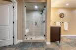 Step into this luxurious bathroom featuring a spacious glass-enclosed shower with multiple showerheads and a built-in bench.