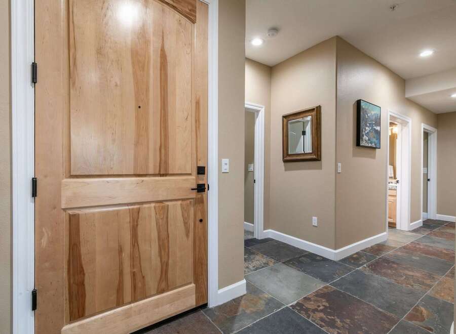 Step into this inviting entryway featuring a beautiful natural wood door and elegant slate tile flooring.