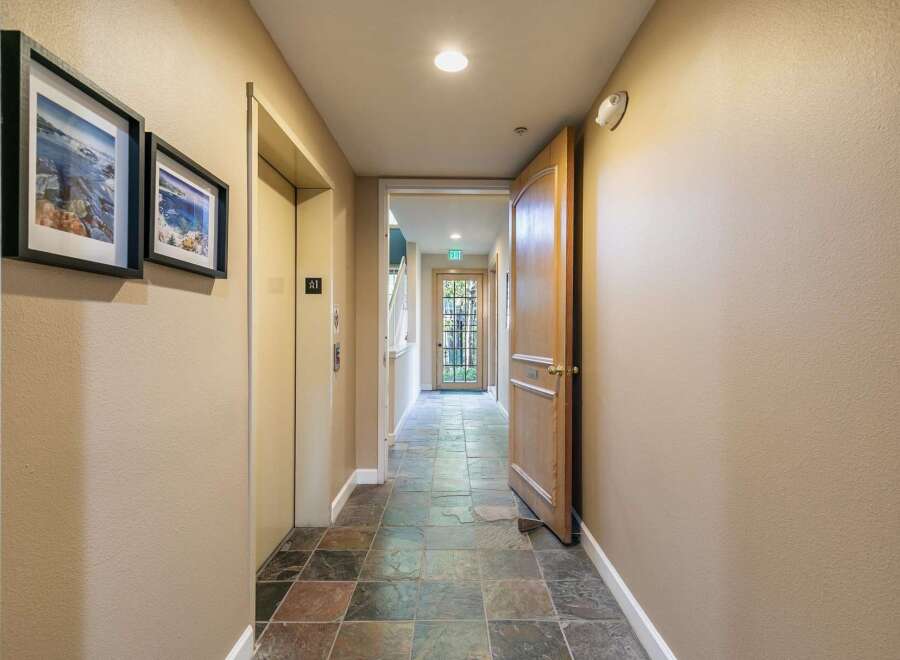 Step into this inviting hallway featuring a convenient elevator and a charming wooden door leading to an outdoor space.