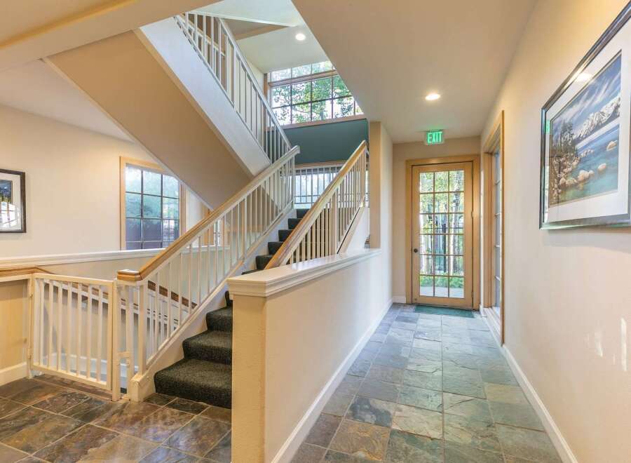 This interior features a multi-level staircase with carpeted steps and white railings, leading up to a large window with a scenic view.