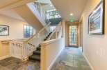 This interior features a multi-level staircase with carpeted steps and white railings, leading up to a large window with a scenic view.