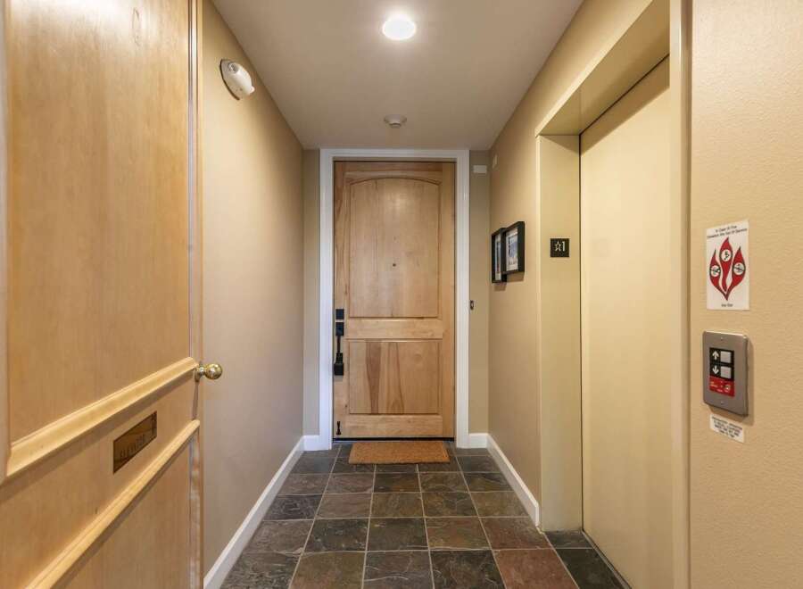 Discover this charming hallway featuring a sturdy wooden door and a convenient elevator.
