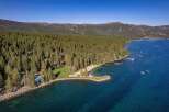 Experience luxury lakeside living with this stunning aerial view of a private beach and pool area nestled within a dense pine forest.