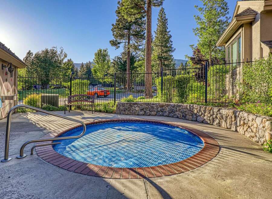 Enjoy a refreshing dip in this inviting circular spa, complete with a protective blue cover and convenient stainless steel handrails for easy access.
