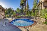 Enjoy a refreshing dip in this inviting circular spa, complete with a protective blue cover and convenient stainless steel handrails for easy access.