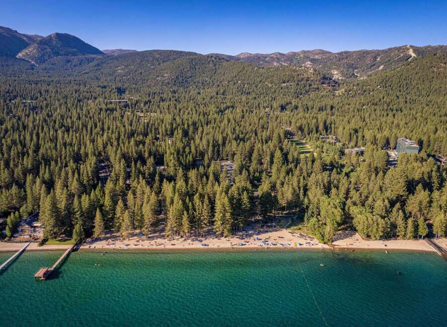 Experience the ultimate lakeside lifestyle with this stunning aerial view of a pristine beach and crystal-clear turquoise waters.