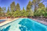 Enjoy a refreshing dip in this stunning outdoor swimming pool, surrounded by lush green trees and a clear blue sky.