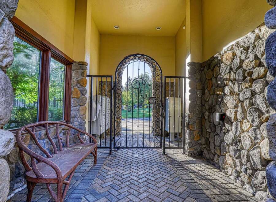 Discover elegant living with this charming entryway featuring a rustic wooden bench and a decorative wrought iron gate.