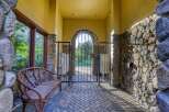 Discover elegant living with this charming entryway featuring a rustic wooden bench and a decorative wrought iron gate.