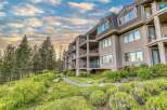 Experience luxury living in this stunning multi-story condo complex nestled amidst lush greenery and towering pine trees.