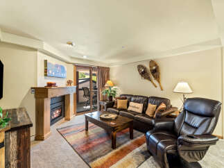 Cozy up by the fireplace in this inviting living room, featuring plush leather seating and a rustic wooden mantel.