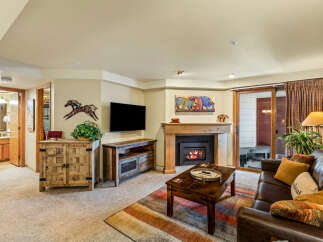 Cozy up by the fireplace in this inviting living room, featuring a comfortable leather sofa and a rustic wooden coffee table.