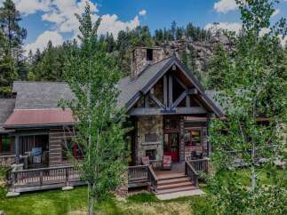 Experience rustic luxury in this stunning mountain lodge, featuring a grand stone fireplace and exposed timber beams.