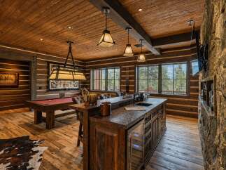 Experience rustic luxury in this stunning game room, featuring a classic pool table and a custom bar with a built-in wine fridge.