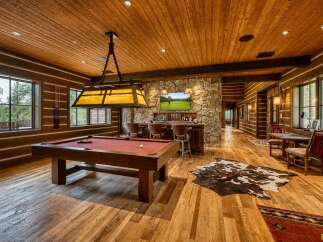 Experience ultimate relaxation in this stunning log cabin game room, featuring a full-size pool table and a well-appointed bar area perfect for entertaining.