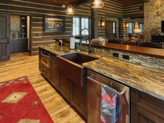 Experience rustic luxury in this stunning log cabin kitchen, featuring a large copper farmhouse sink and exquisite granite countertops.