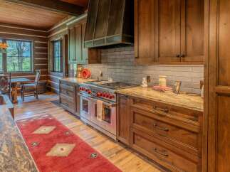 Experience rustic charm in this spacious log cabin kitchen, featuring rich wood cabinetry and a professional-grade Wolf range.