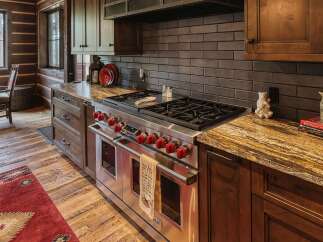 Experience rustic charm in this stunning log cabin kitchen, featuring a professional-grade Wolf range and beautiful granite countertops.