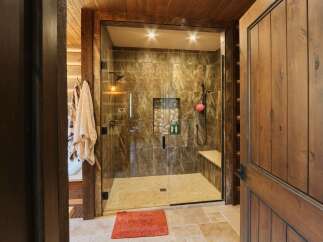 Step into a luxurious spa-like bathroom featuring a spacious glass-enclosed shower with marble-look tiles and a built-in bench.