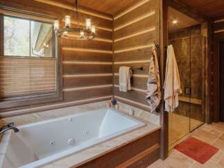 Experience rustic luxury in this stunning bathroom featuring a deep soaking tub and a spacious walk-in shower with elegant tilework.