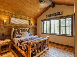 Experience rustic charm in this cozy bedroom, featuring a log-style bed adorned with a Southwestern-patterned quilt and pillows.