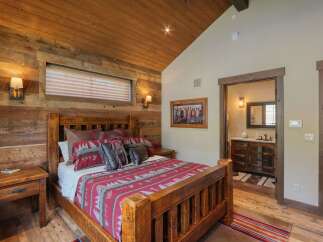 Experience rustic charm in this master bedroom featuring a stunning wooden bed adorned with a Native American-inspired blanket and pillows.