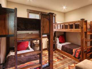 This rustic bedroom features two sets of sturdy wooden bunk beds, perfect for accommodating family or guests.
