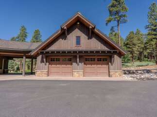 This rustic mountain home features a charming two-car garage with traditional wooden doors and stone accents.