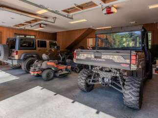 This spacious garage offers ample storage for all your recreational vehicles, including a Jeep, a riding mower, and a Polaris UTV.