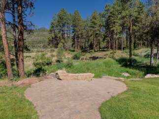 Enjoy the serene natural beauty of this property from a charming stone patio, perfect for outdoor relaxation.