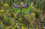 Nestled amidst a lush forest, this stunning property features a beautiful home with a charming porch and a stone chimney.